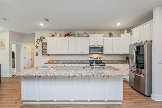 602 Champ Trl, Crestview, FL 32539 - kitchen with appliances with stainless steel finishes, white cabinets, light wood-style flooring, a kitchen island with sink, and recessed lighting