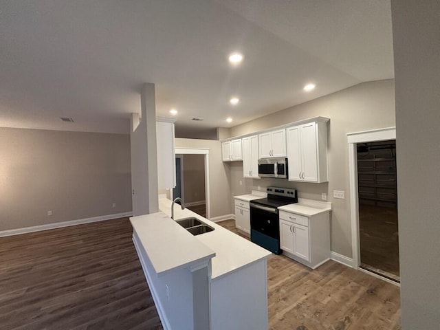 kitchen with appliances with stainless steel finishes, a sink, dark wood-type flooring, white cabinetry, and light countertops