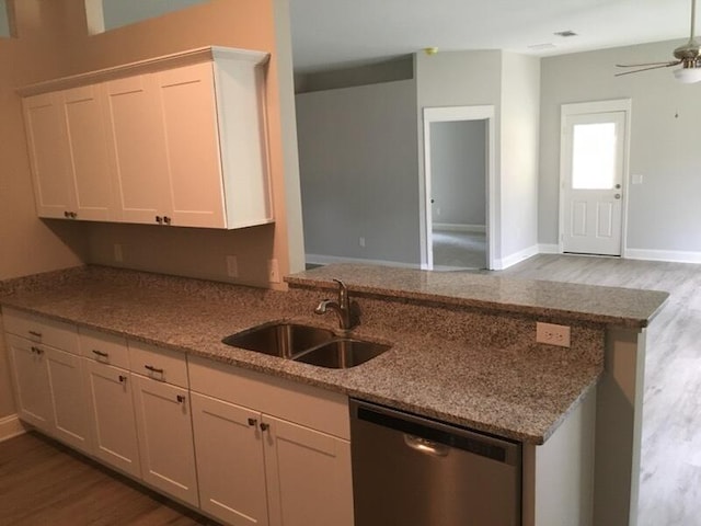 kitchen with stainless steel dishwasher, a sink, wood finished floors, a ceiling fan, and a peninsula