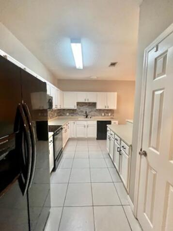 1413 Beaver Run Rd Unit 7, Niceville, FL 32578 - kitchen with black appliances, white cabinetry, light tile patterned floors, backsplash, and light countertops
