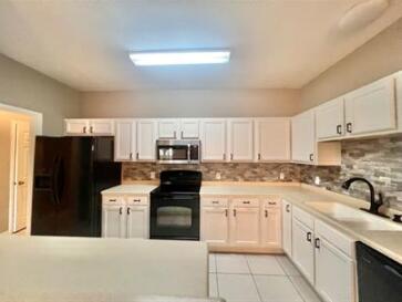 1413 Beaver Run Rd Unit 7, Niceville, FL 32578 - kitchen featuring black appliances, a sink, white cabinetry, and backsplash
