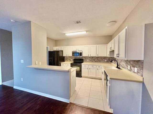 1413 Beaver Run Rd Unit 7, Niceville, FL 32578 - kitchen with black appliances, tasteful backsplash, light countertops, white cabinetry, and light wood-type flooring