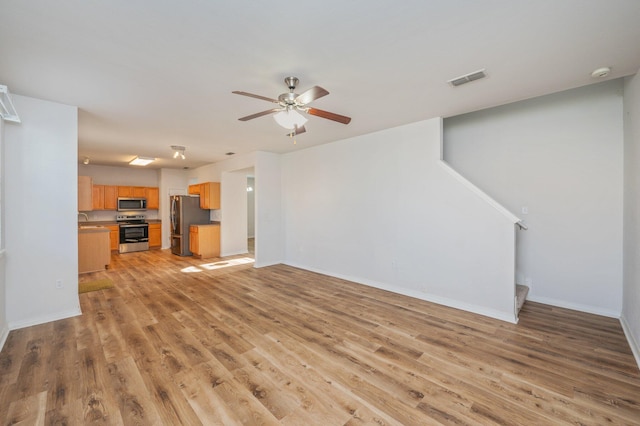 613 Prairie St, Crestview, FL 32536 - unfurnished living room featuring light wood-type flooring, ceiling fan, baseboards, stairs, and a sink