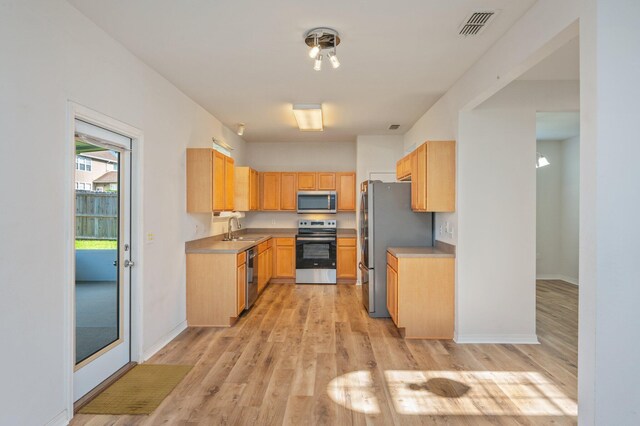 613 Prairie St, Crestview, FL 32536 - kitchen with appliances with stainless steel finishes, a sink, light wood-style flooring, light brown cabinetry, and baseboards