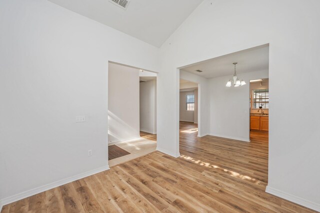 613 Prairie St, Crestview, FL 32536 - unfurnished room with a chandelier, light wood-style floors, lofted ceiling, and baseboards