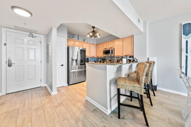 4207 Indian Bayou Trl Unit 2513, Destin, FL 32541 - kitchen featuring appliances with stainless steel finishes, light brown cabinets, a breakfast bar, light wood finished floors, and a peninsula