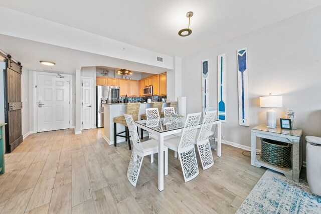 4207 Indian Bayou Trl Unit 2513, Destin, FL 32541 - dining space with a barn door, light wood-type flooring, and baseboards