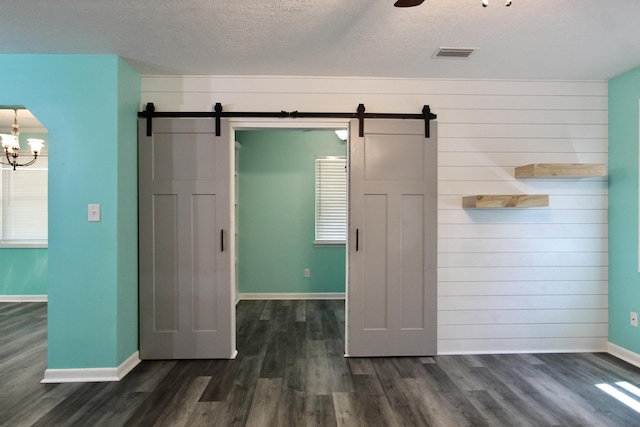 3961 Painter Branch Rd, Crestview, FL 32539 - unfurnished bedroom with a barn door, dark wood-style floors, baseboards, a textured ceiling, and wood walls