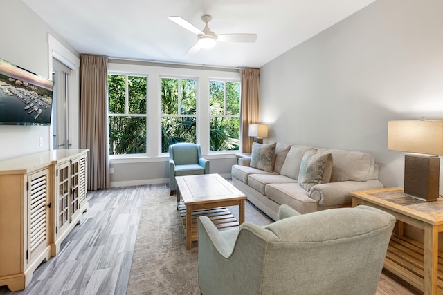 living room with light wood-type flooring, a ceiling fan, and baseboards