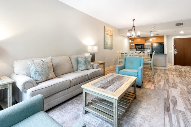 living room featuring a chandelier, light wood finished floors, and baseboards