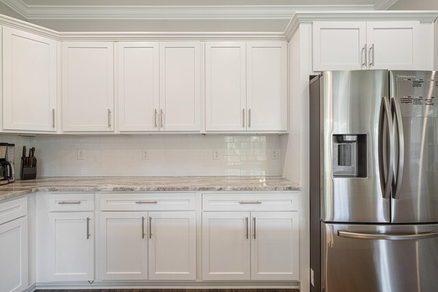 410 Coastal Breeze Dr, Freeport, FL 32439 - kitchen featuring stainless steel refrigerator with ice dispenser, white cabinets, backsplash, light stone counters, and ornamental molding