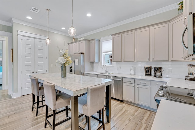 kitchen with appliances with stainless steel finishes, a sink, wood finish floors, light countertops, and decorative backsplash