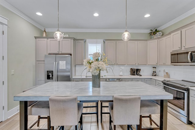 kitchen featuring stainless steel appliances, backsplash, light countertops, a breakfast bar, and pendant lighting