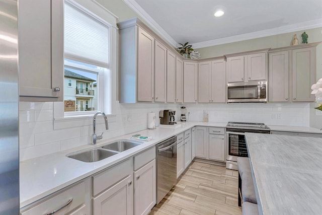 kitchen featuring stainless steel appliances, a sink, light countertops, crown molding, and backsplash