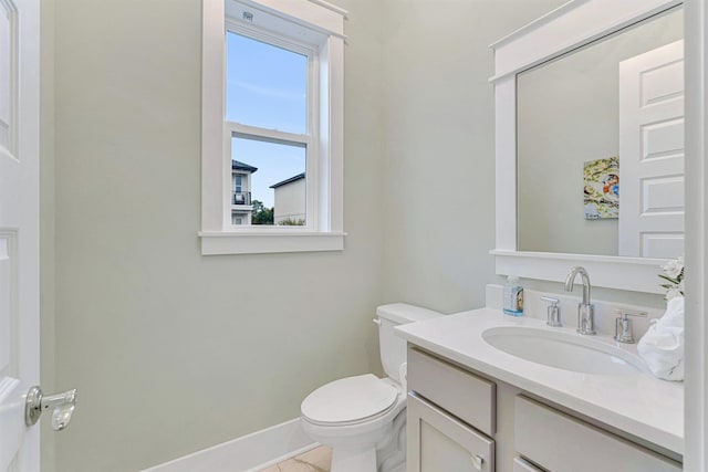 half bath with toilet, baseboards, and vanity