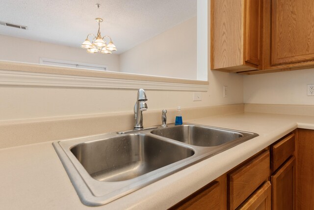 282 Swaying Pine Ct, Crestview, FL 32539 - kitchen featuring a sink, light countertops, brown cabinetry, a chandelier, and pendant lighting