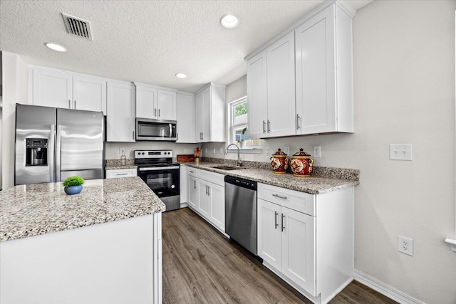 3163 Haskell Langley Rd, Crestview, FL 32539 - kitchen featuring stainless steel appliances, a sink, dark wood-style floors, white cabinets, and light stone countertops
