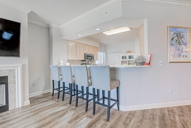 8601 Surf Dr Unit 2W, Panama City Beach, FL 32408 - kitchen with stainless steel microwave, light wood-style floors, ornamental molding, a breakfast bar area, and light countertops
