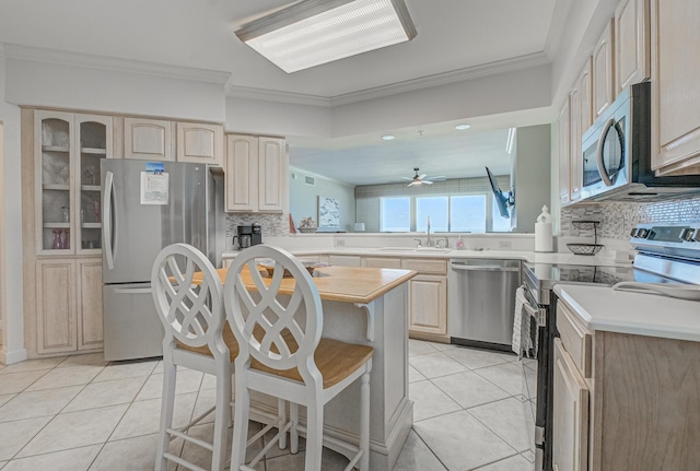 8601 Surf Dr Unit 2W, Panama City Beach, FL 32408 - kitchen with stainless steel appliances, light brown cabinetry, ornamental molding, a sink, and light tile patterned floors