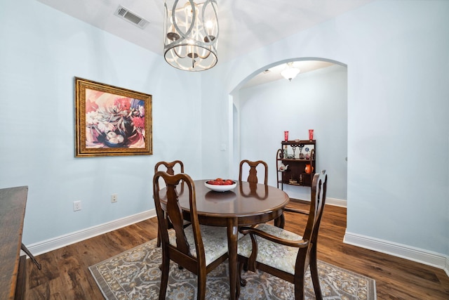 dining room featuring arched walkways, baseboards, a chandelier, and dark wood-type flooring
