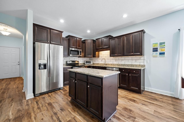 kitchen with stainless steel appliances, dark brown cabinets, tasteful backsplash, dark wood-type flooring, and recessed lighting