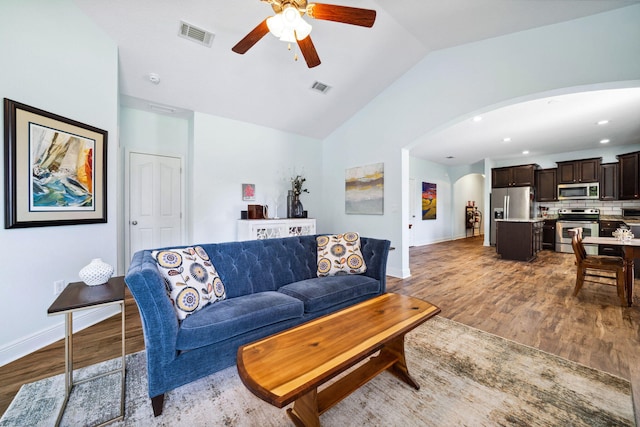 living area with a ceiling fan, arched walkways, wood finished floors, lofted ceiling, and baseboards