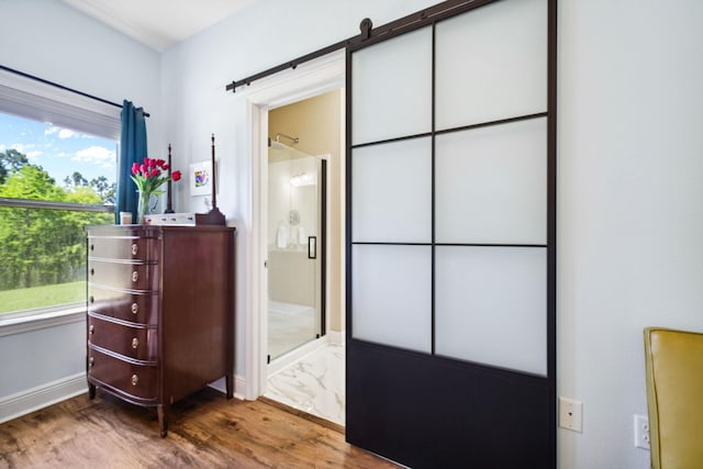 bedroom with wood finished floors, baseboards, and ensuite bath
