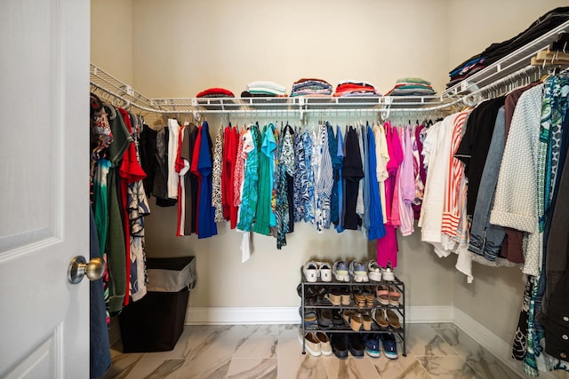 walk in closet featuring marble look tiles