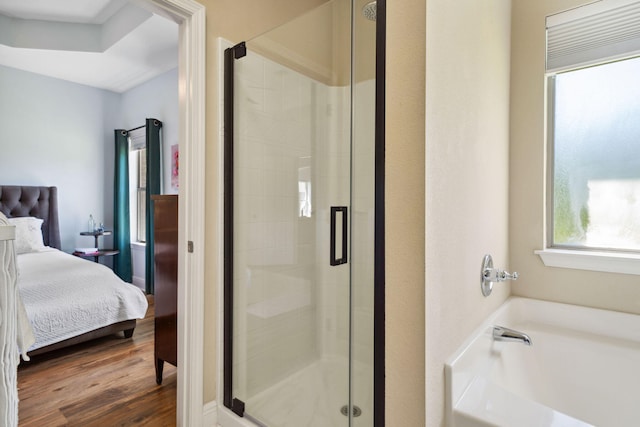 ensuite bathroom featuring a stall shower, a bath, and wood finished floors