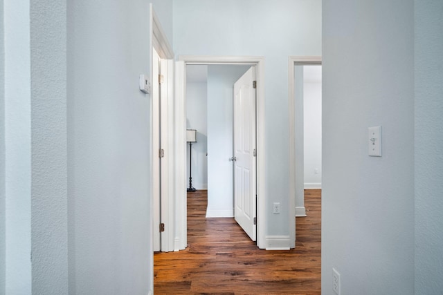 corridor with dark wood-style floors and baseboards