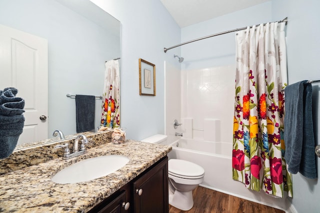 bathroom with toilet, wood finished floors, shower / tub combo, and vanity
