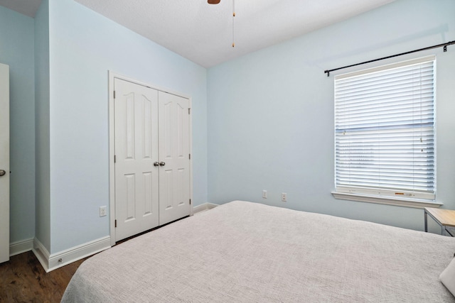 bedroom featuring dark wood finished floors, a closet, baseboards, and ceiling fan