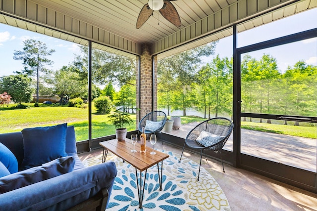 sunroom / solarium featuring ceiling fan, healthy amount of natural light, and view of wooded area