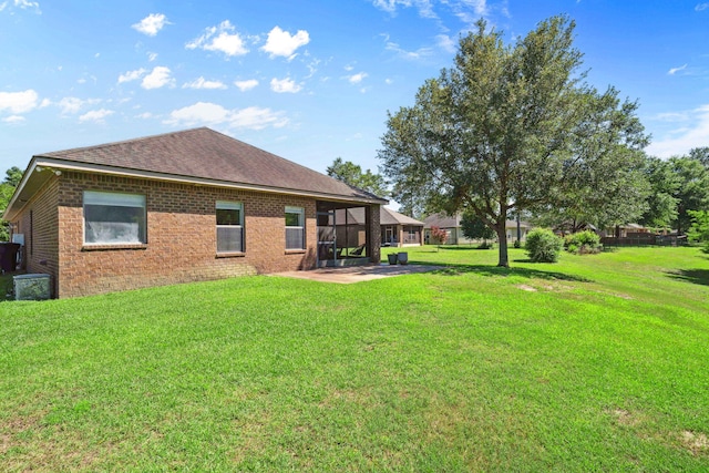 back of house with a patio, brick siding, and a yard