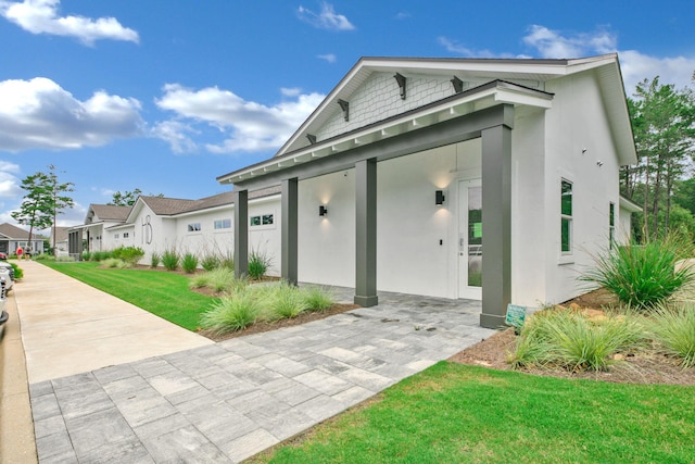 view of front of house featuring stucco siding, a front yard, and a residential view