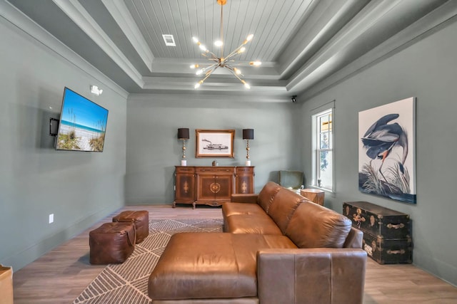 living room featuring a raised ceiling, a chandelier, wood finished floors, wood ceiling, and ornamental molding