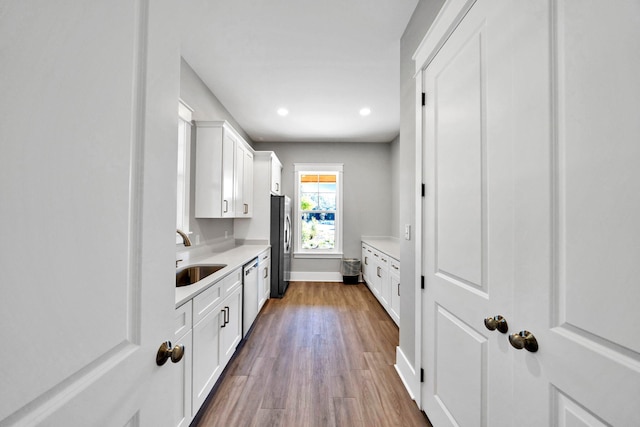 kitchen with stainless steel appliances, a sink, light countertops, dark wood-style flooring, and white cabinets