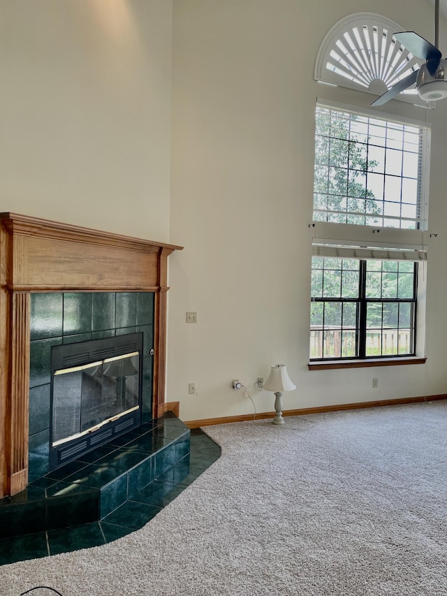 5882 Willow Ln, Crestview, FL 32539 - unfurnished living room with a towering ceiling, carpet floors, a tiled fireplace, and baseboards