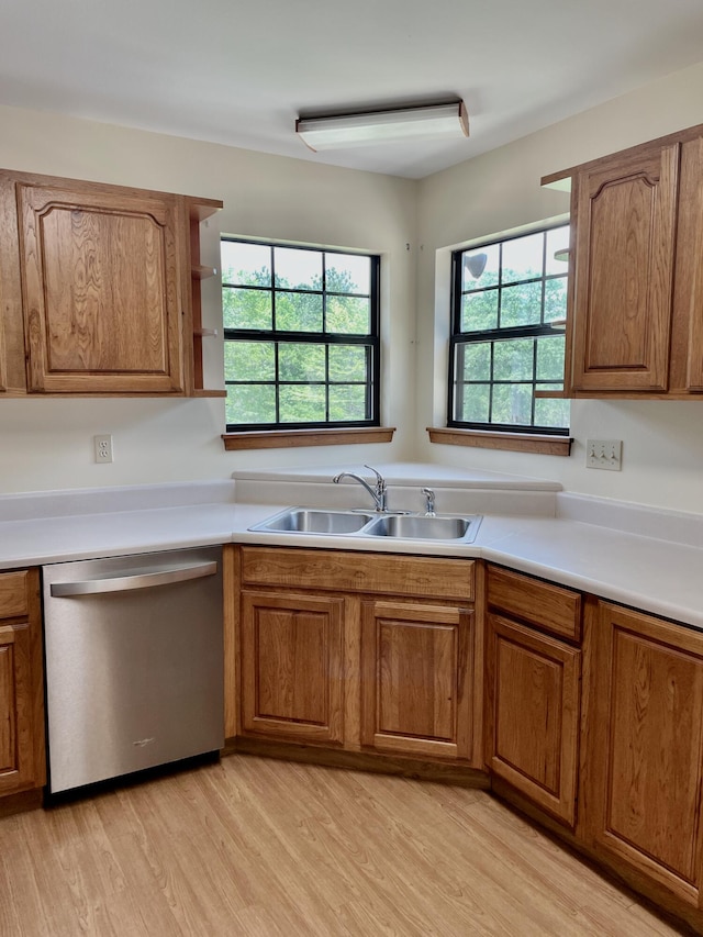 5882 Willow Ln, Crestview, FL 32539 - kitchen with stainless steel dishwasher, a sink, brown cabinetry, light wood-style flooring, and light countertops