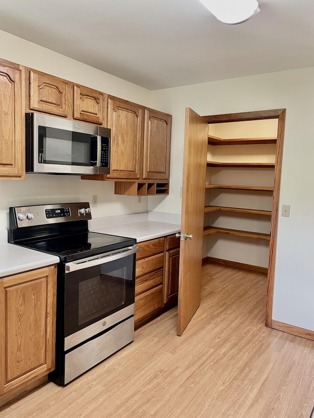 5882 Willow Ln, Crestview, FL 32539 - kitchen with appliances with stainless steel finishes, light wood finished floors, light countertops, and brown cabinetry