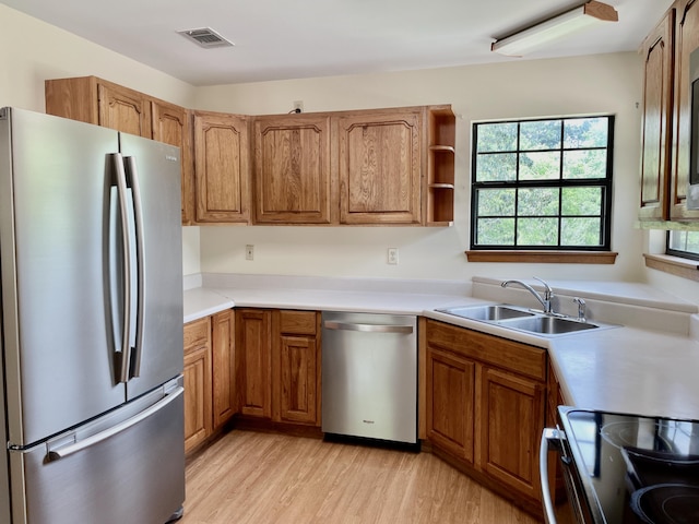 5882 Willow Ln, Crestview, FL 32539 - kitchen featuring stainless steel appliances, a sink, brown cabinets, light wood-style flooring, and light countertops