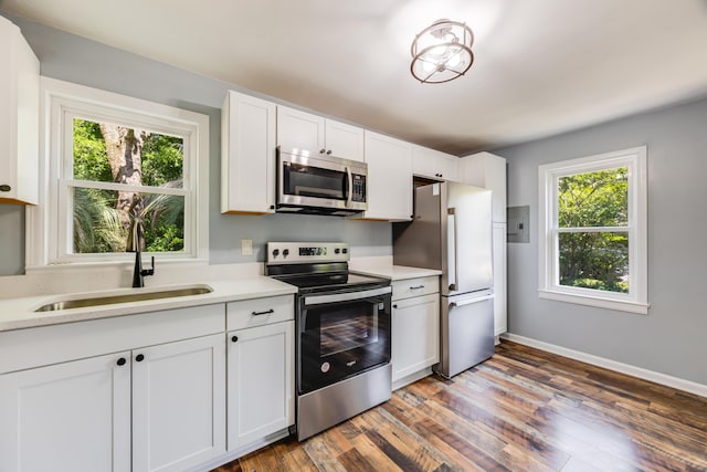 kitchen with stainless steel appliances, a sink, light countertops, wood finished floors, and white cabinets