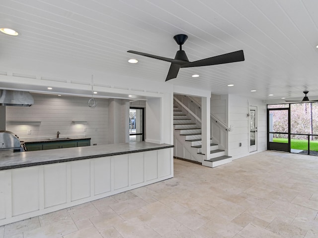 173 Crissman Rd, Santa Rosa Beach, FL 32459 - kitchen with dark countertops, a ceiling fan, wall chimney exhaust hood, recessed lighting, and light stone finish floors