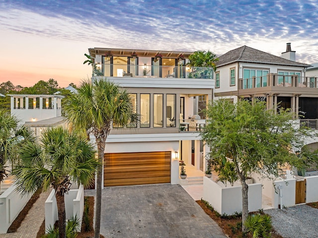 238 Sand Oaks Cir, Santa Rosa Beach, FL 32459 - view of front of property featuring a balcony, driveway, a fenced front yard, an attached garage, and stucco siding