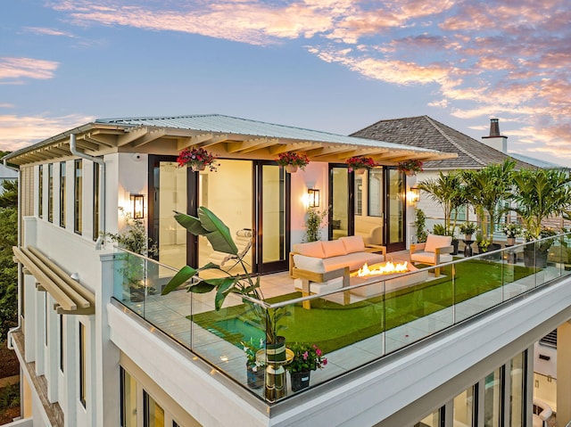 238 Sand Oaks Cir, Santa Rosa Beach, FL 32459 - back of house at dusk with a balcony, a chimney, and an outdoor living space with a fire pit