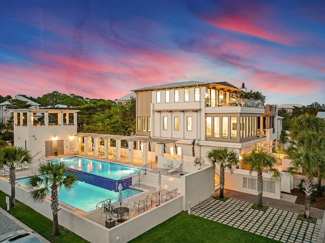 238 Sand Oaks Cir, Santa Rosa Beach, FL 32459 - back of property at dusk featuring a community pool, a patio area, and a balcony