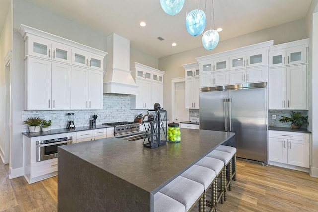 336 S Holiday Rd, Destin, FL 32550 - kitchen featuring dark countertops, premium appliances, custom exhaust hood, backsplash, and an island with sink