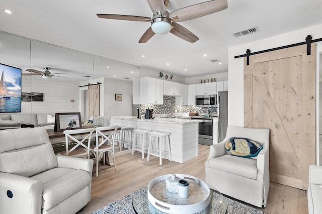 2384 Scenic Gulf Dr Unit C308, Miramar Beach, FL 32550 - living room featuring a barn door, ceiling fan, and light wood-style floors