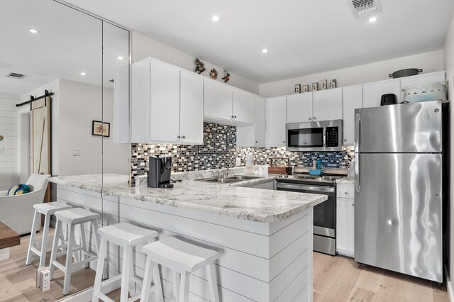 2384 Scenic Gulf Dr Unit C308, Miramar Beach, FL 32550 - kitchen with appliances with stainless steel finishes, a sink, a peninsula, a barn door, and light wood-type flooring