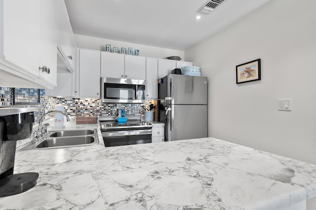 2384 Scenic Gulf Dr Unit C308, Miramar Beach, FL 32550 - kitchen with appliances with stainless steel finishes, a sink, decorative backsplash, white cabinets, and light stone counters